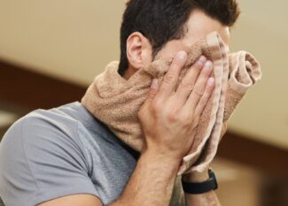 Homem limpando o suor do rosto com uma toalha